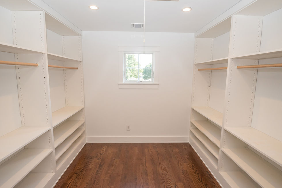 Empty walk-in closet with wooden floor.