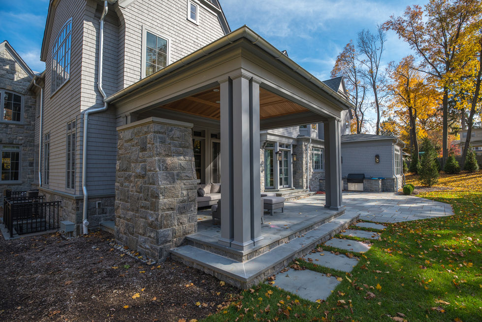 Covered patio with stone pillars and wooden ceiling.