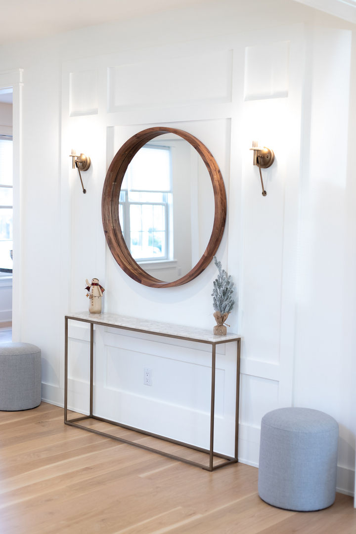Round mirror above minimalist console table and decor.