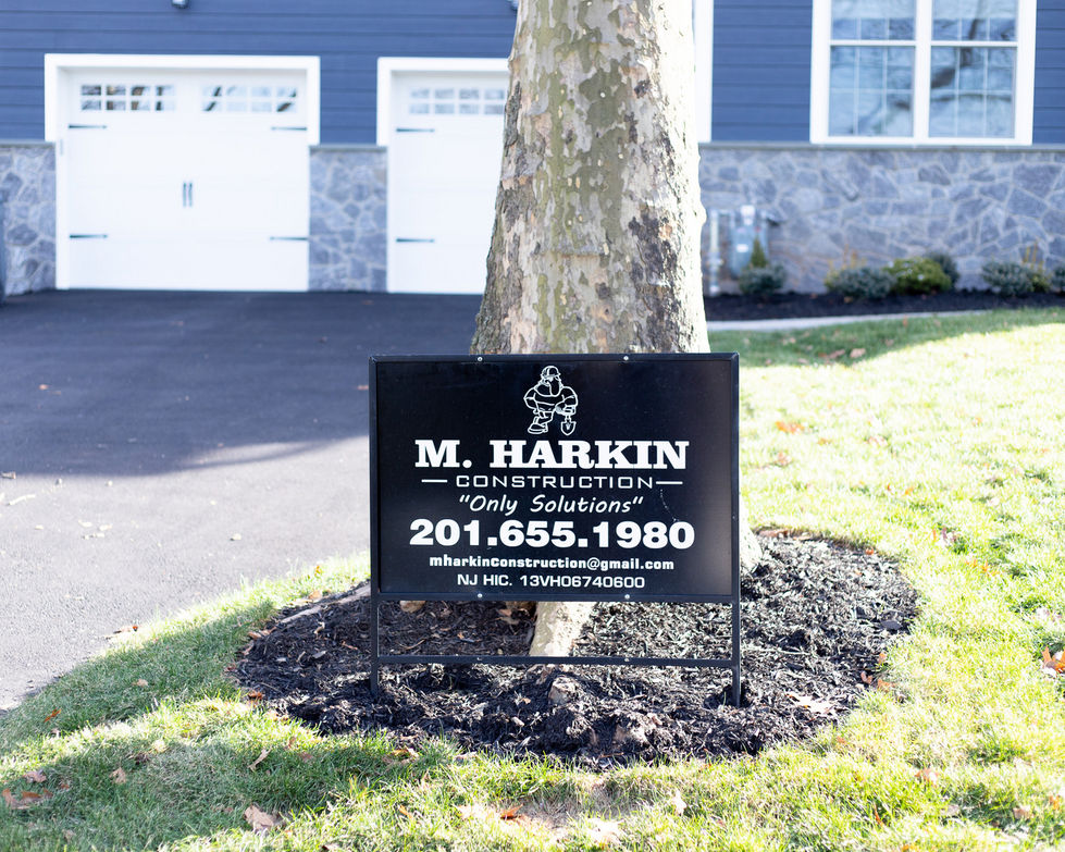 Sign for M. Harkin Construction near a tree.