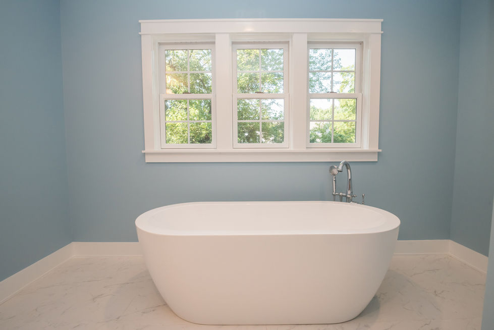 Freestanding bathtub in front of a window.