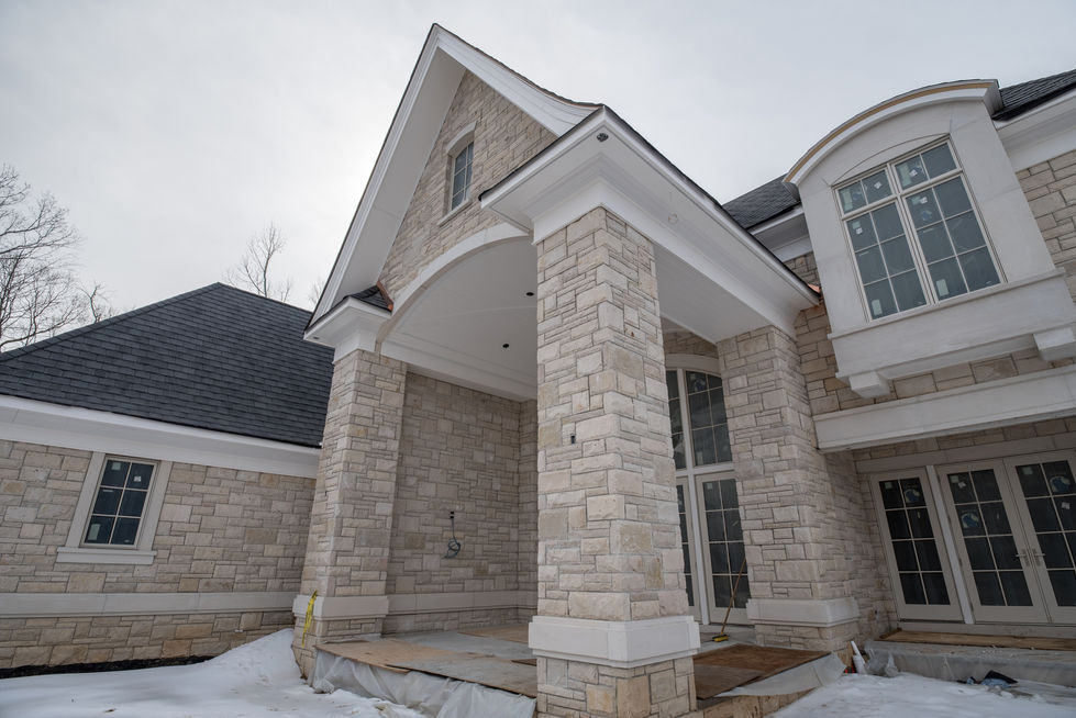Stone house with large columns and arched entrance.