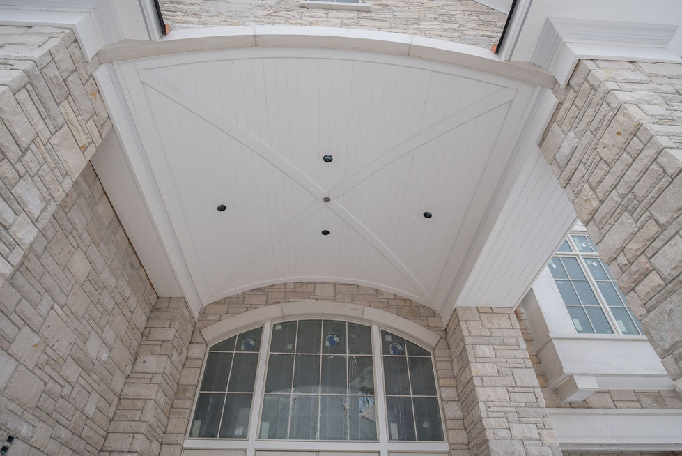 Stone house entrance with arched window and ceiling.