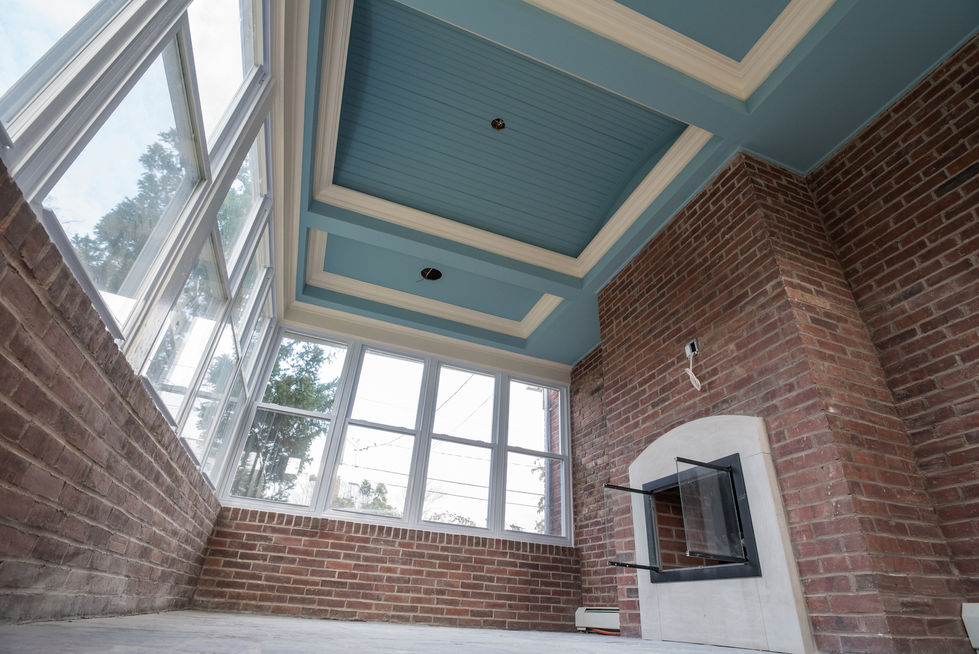 Brick sunroom with large windows and blue ceiling.