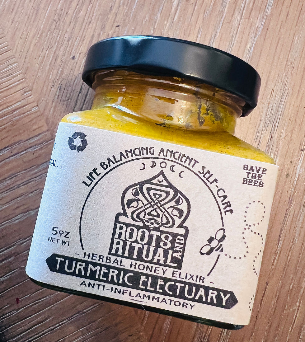 Jar of yellow turmeric electuary on wooden surface. Label reads "Roots and Ritual," "Herbal Honey Elixir," "Anti-inflammatory," with bee design.