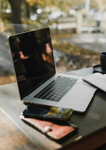 A laptop and phones on a cafe table, representing a flexible work environment and the modern approach to career coaching.