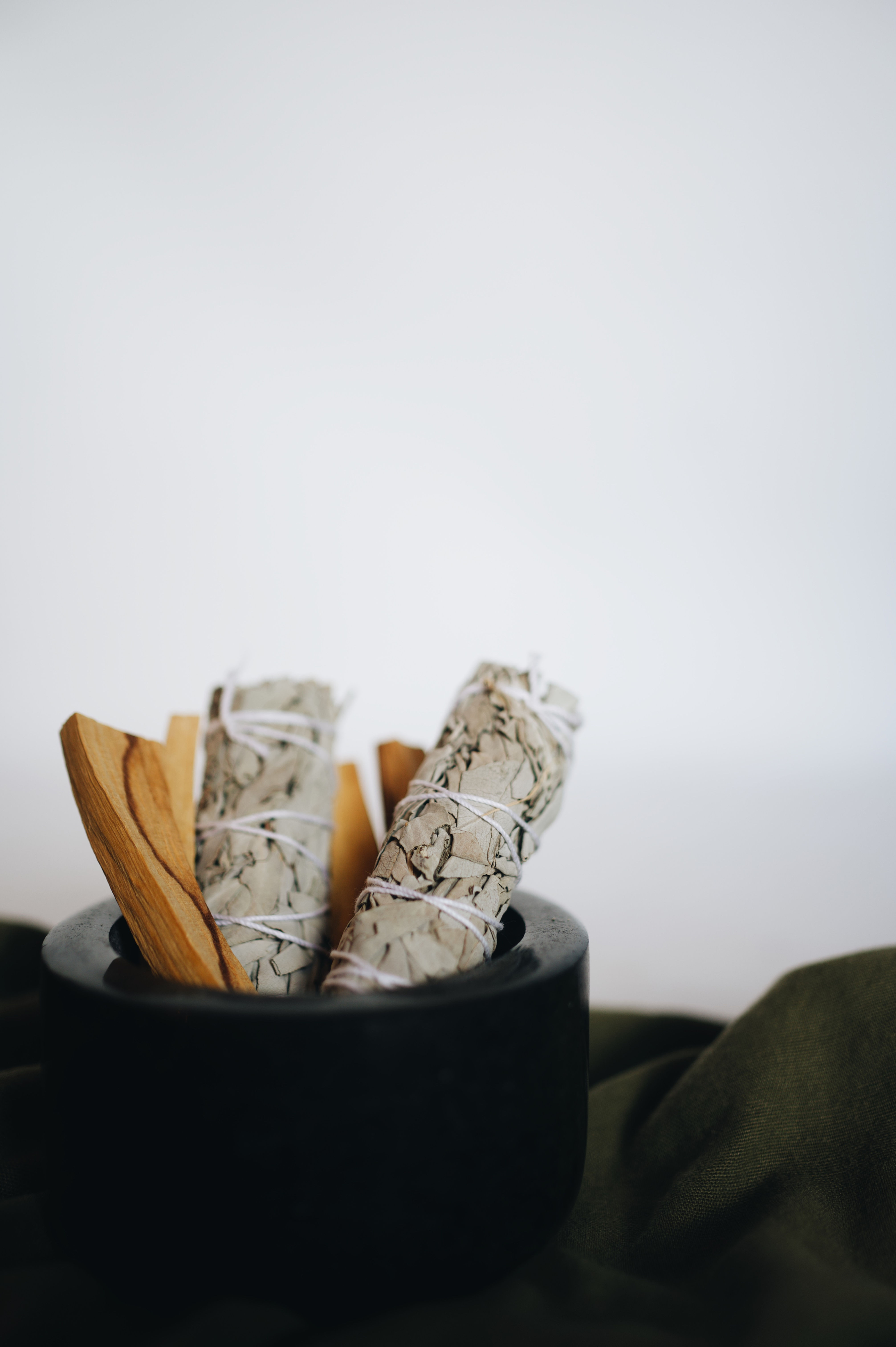 2 white sage sticks in a blowl with Palo Santo sticks for contrast