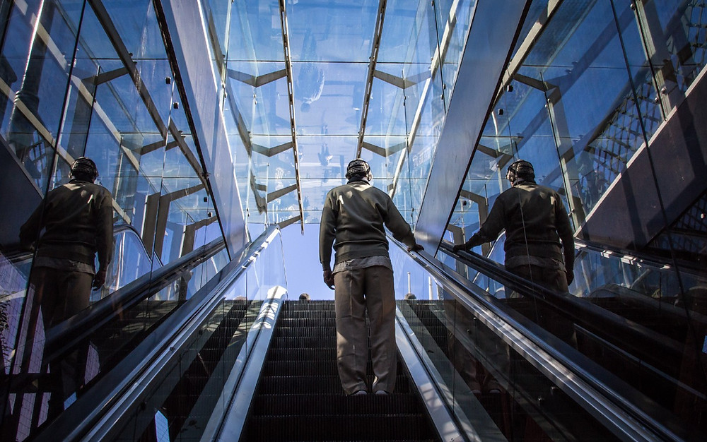 A man standing on an upwards escalator