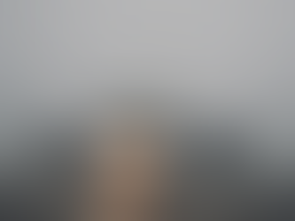 A commercial airplane taxiing on a foggy runway with low visibility and runway lights faintly visible through the mist.