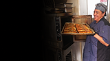 Smiling chef holding a tray of grilled salmon