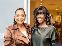 Two smiling women standing together  in the recent Christmas Between Investor Luncheon