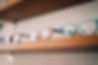Colourful glasses displayed on wooden shelf.