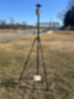 Close-up view of a GNSS receiver mounted on a survey pole in a grassy field