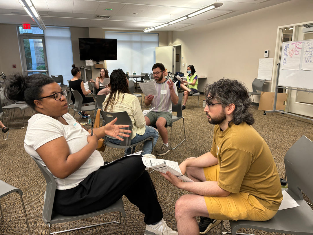 Groups of people engaged in discussion during a training event taking place in a classroom.
