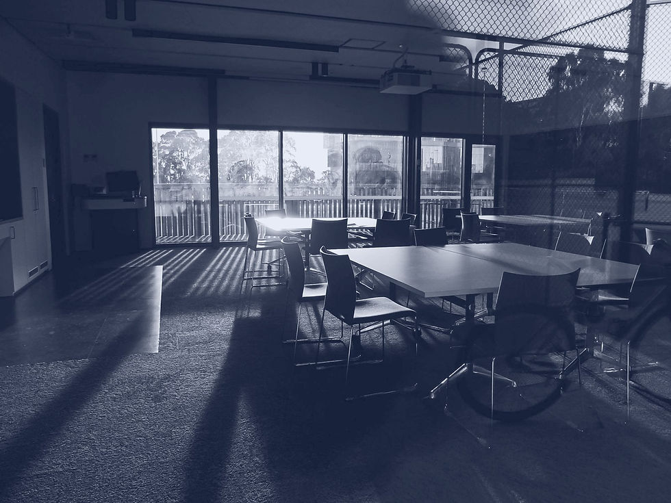 An empty meeting room with chairs left at angles around the tables and low sunlight across the floor