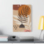 A framed abstract artwork featuring earthy tones of beige, brown, and orange, with black botanical elements. The composition includes a stylized plant with dark leaves emerging from a patterned pot, geometric shapes, and organic forms. The artwork is displayed on a minimalist white shelf, accompanied by pastel-colored vases holding yellow spherical flowers and green leafy stems, creating a modern and aesthetically pleasing arrangement.