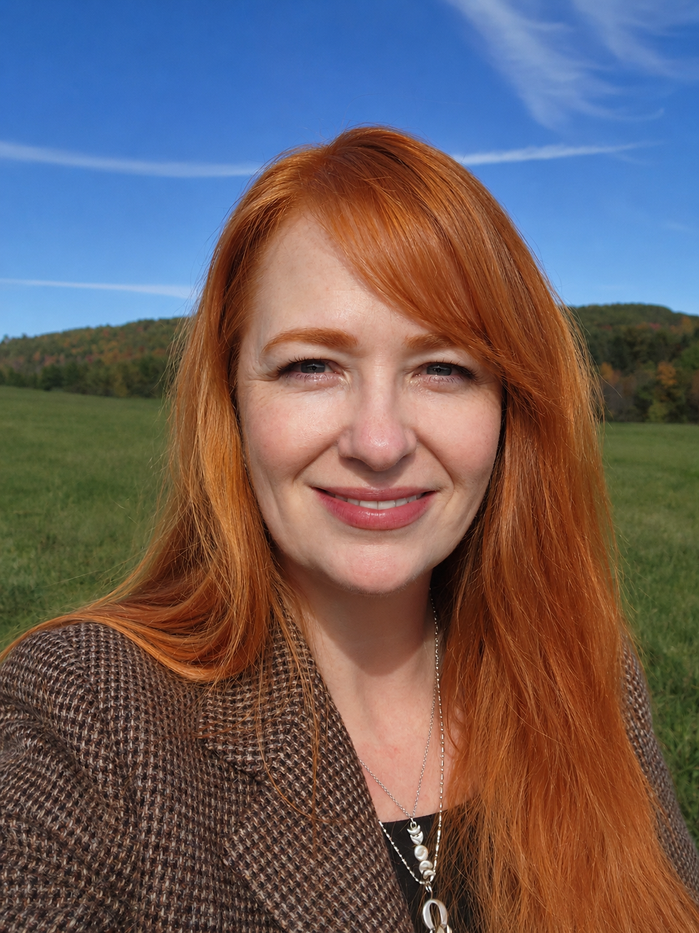 Portrait photo of Heather Young outdoors with blue sky and green field background