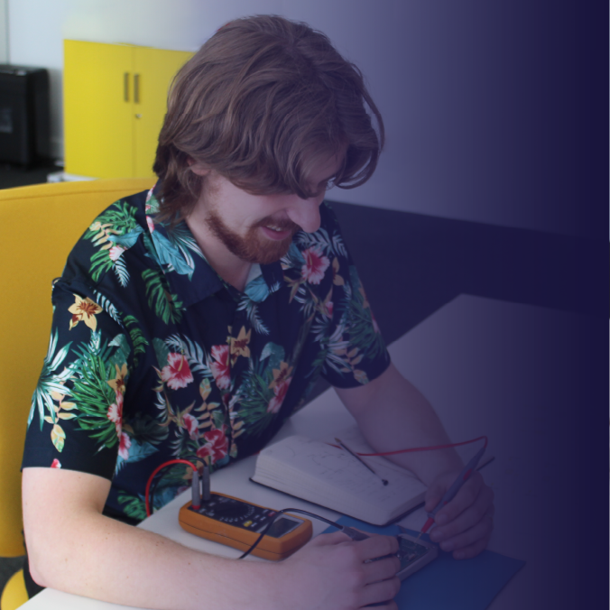 Smiling engineer testing electronics at a desk