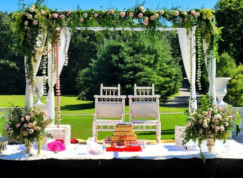 "Vrindavan Green" is an elegant and lush mandapa design, featuring an abundance of green foliage that creates a natural and serene ambiance. The mandapa is accented with a sleek white sheet design that adds a touch of elegance and sophistication. The design takes inspiration from the mystical town of Vrindavan, known for its beautiful gardens and temples. The use of green foliage gives a natural and fresh look to the mandapa, representing new beginnings and growth. Customization is available with this design, allowing clients to choose their preferred colors to match their wedding theme and personal style. This mandapa design is perfect for those looking to incorporate a touch of nature and elegance into their special day.