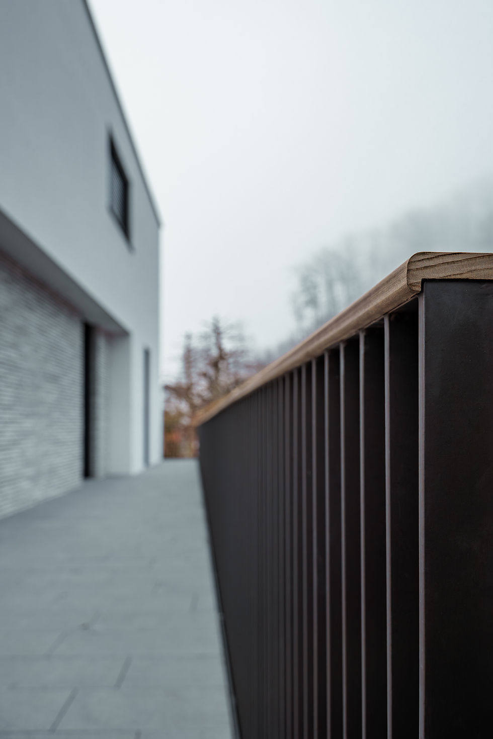 Detailed architectural photograph of a dark metal railing and brick facade at a modern private residence in Lucerne, showcasing precision metalwork by Hobler Metallbau AG.