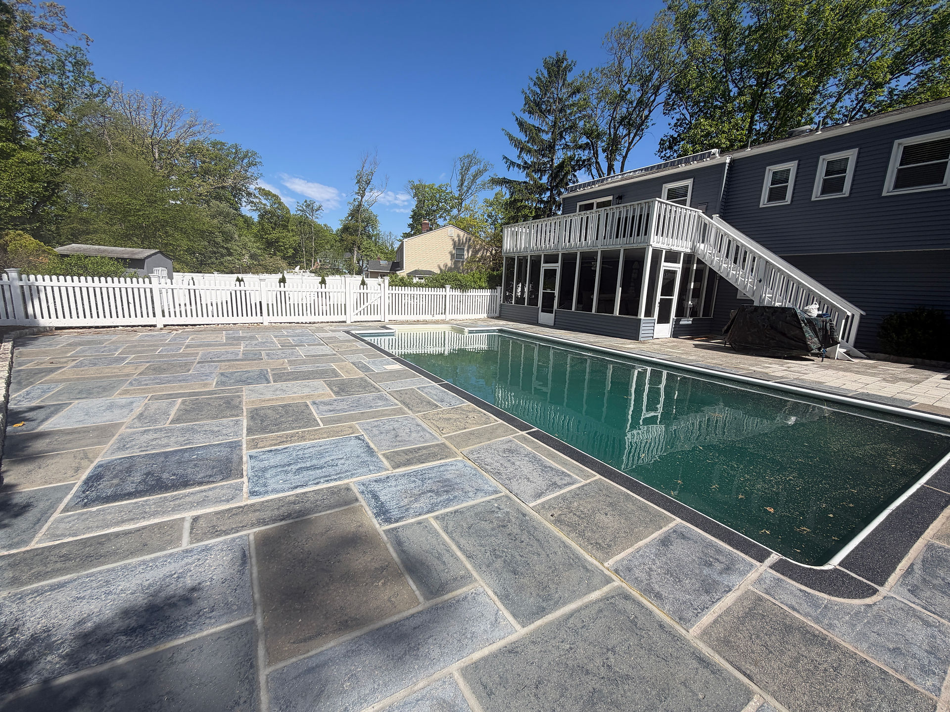 Wide RenuKrete pool deck resurfacing with a stone-look concrete overlay beside an in-ground pool