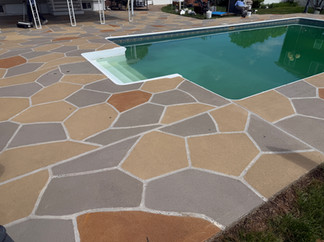 Pool with diving board surrounded by a Hurricane Slate flagstone deck resurfaced by RenuKrete.