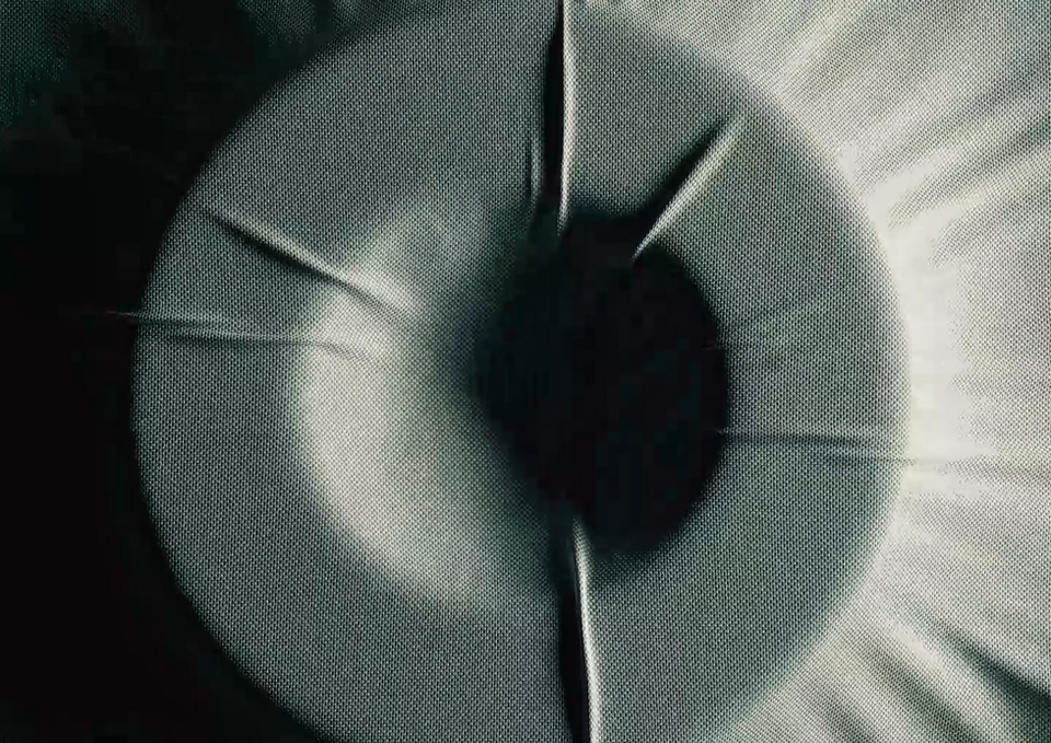 Close-up of headphone ear cushion texture showing detailed fabric tension and soft mesh material in dramatic lighting