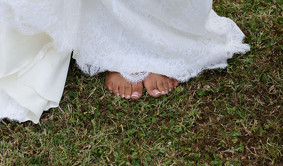 piedi nudi ben curati con french su un prato verde di una sposa. L'abito bianco appena sollevato mostra i piedi