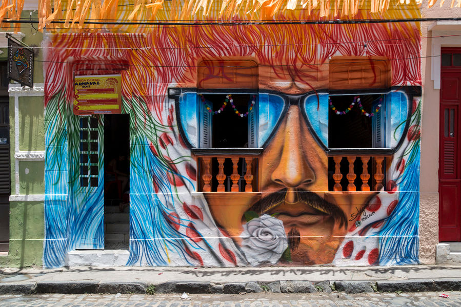 Uma casa do centro histórico de Olinda foi pintada com um grafite que representa o rosto de um caboclo de lança do Maracatu de Baque Solto. O homem do desenho usa bigode. Tem uma flor branca na boca e um lenço sobre a cabeça, amarrado por baixo do queixo. Ele também usa óculos escuros e as lentes dos óculos coincidem com os vãos das janelas da casa.