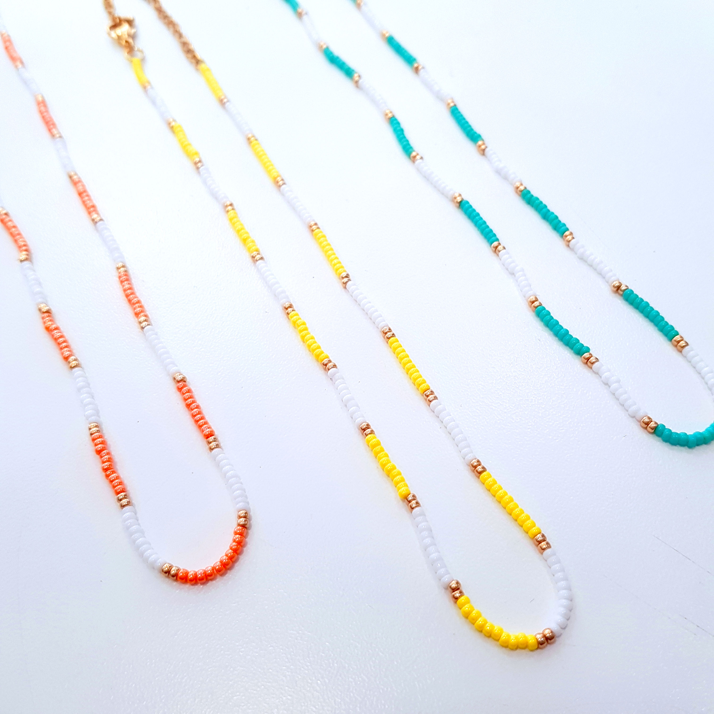 3 Ras de cou en perles : 1 blanc doré et orange, 1 blanc doré et jaune, 1 blanc doré et vert. Couleurs au choix