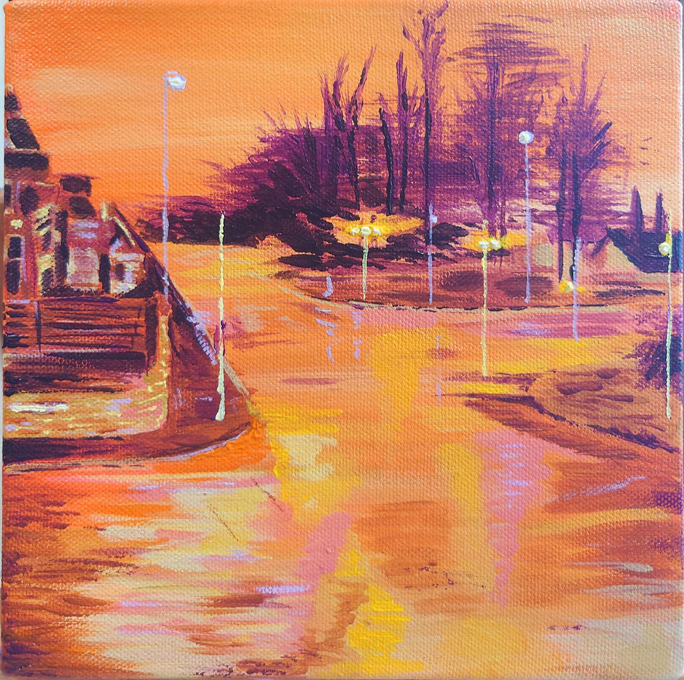 Street at sunset with vibrant orange and purple hues. Trees silhouetted in the background, reflecting light from street lamps on wet pavement.