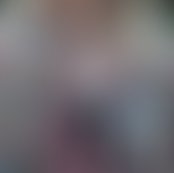 A blond woman dressed in a boho style wears a charm necklace featuring crescent moons, flowers, and pink coloured crystals.