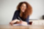 happy-female-college-student-sitting-at-desk-writi-2024-10-17-04-17-58-utc.jpg