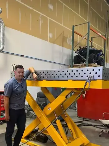 Welder working on a large frame fixture on a DCT welding table, showing strong clamping, accurate alignment, and clean access for production welding.