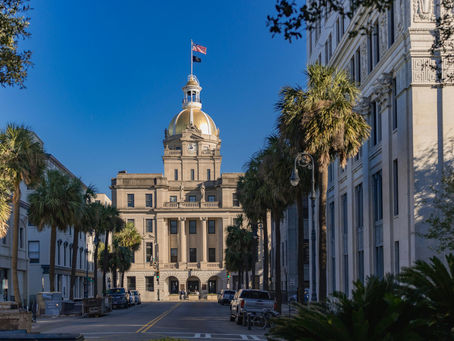 Historic courthouse with a gold dome and American flag, lined with palm trees under a clear blue sky.