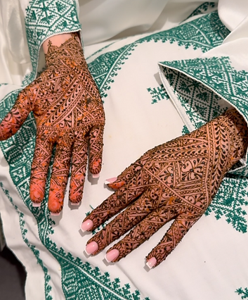 2handen op een kussen waarbij die handen ook versierd zijn met henna. 