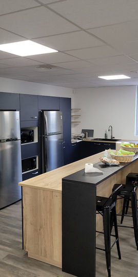 Cuisine équipée avec frigidaires, micro-ondes, lave vaisselle encastré et mange debout