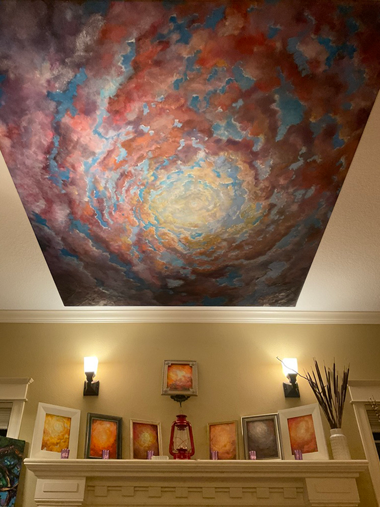 A cloud mural painted across a ceiling above a fireplace