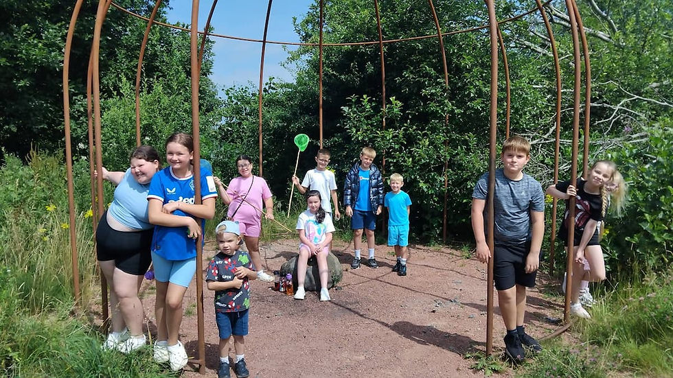 Kids stand around a metal dome in woodlands in summer. Two have fishing nets.