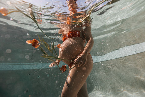 underwater maternity photoshoot in a pool with flowers and tulips