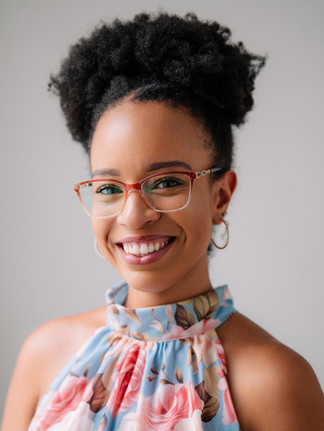Foto de mulher negra, com blusa azul florida e expressão leve e sorridente