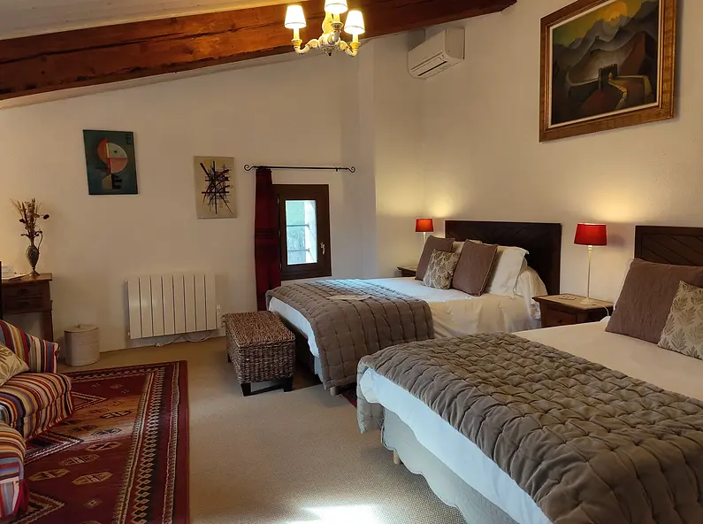 Amplia habitación familiar de lujo Canigou en Thuir con sus dos cómodas camas, aire acondicionado y vigas vistas en la masía rural