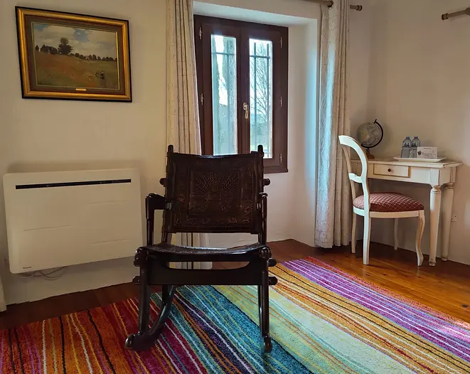 Espace détente de la chambre Colombine avec rocking-chair, tapis et coin bureau