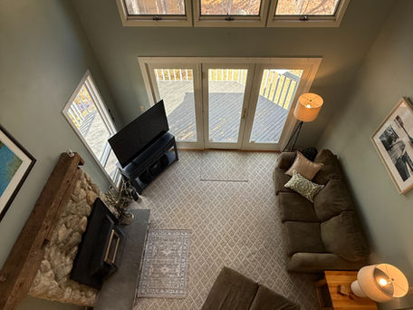 Upper loft looking at the living area with sofas, chair and TV in the Bridgton Maine vacation rental