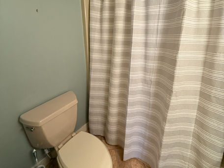 Bathroom with beige toilet and striped shower curtains in Bridgton Maine vacation rental