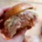 Someone holding a ham and cheese slider
