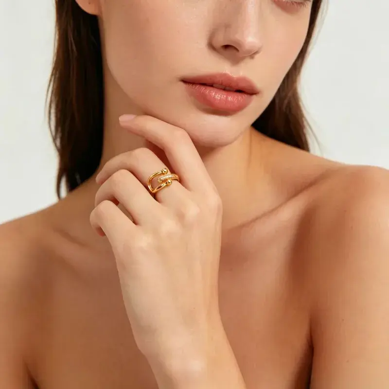 Mão de uma mulher elegante usando o Anel Aberto HardWeare Pavé dourado no dedo anelar, destacando a atitude moderna e o brilh