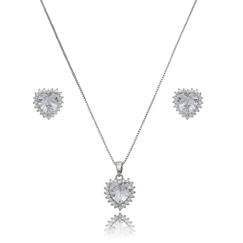 par de brincos e no pingente, evidenciando o detalhe do coração central liso e transparente rodeado pela borda brilhante e te