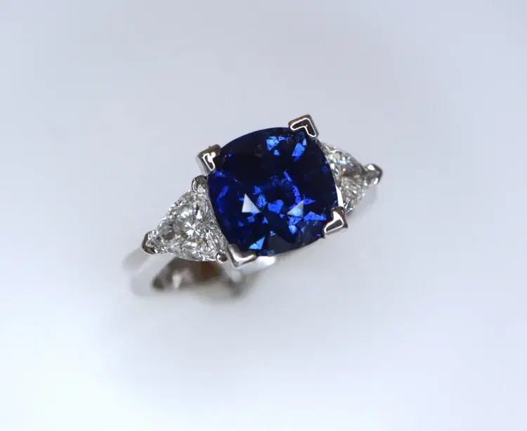 Miniatura: Anel de luxo em ródio branco com design de três pedras. Ao centro, uma grande zircônia safira lapidação cushion