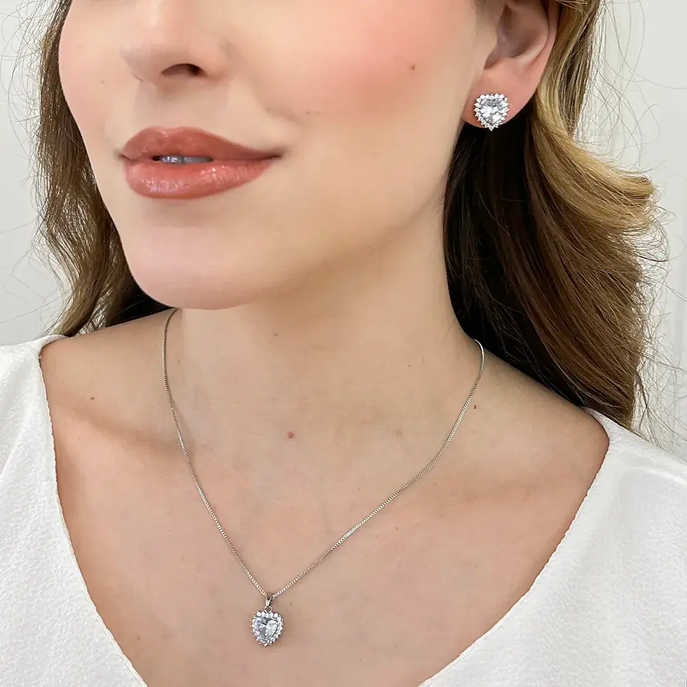 o brinco prateado cravejado ilumina o lóbulo da orelha, enquanto o colar com pingente idêntico repousa delicadamente sobre a